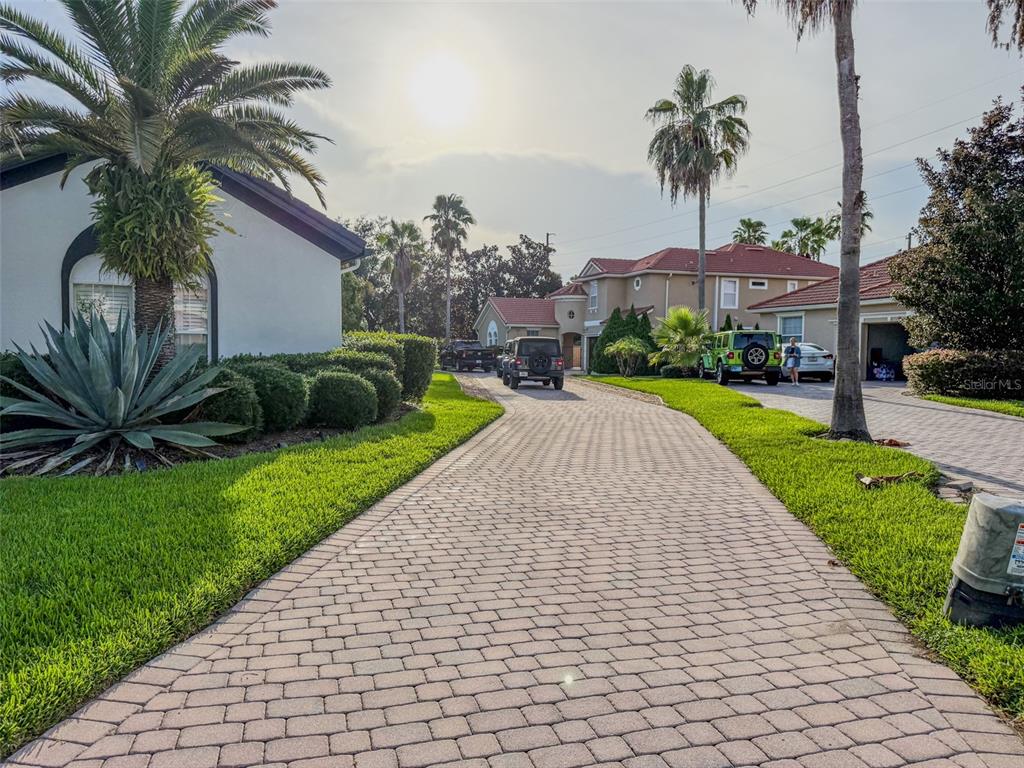 A paved driveway leads toward a two-story house with palm trees and parked vehicles — 11434 RAPALLO LANE, WINDERMERE, FL
