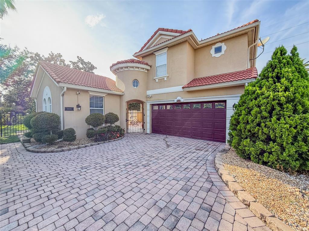 A two-story house with a tiled roof, a brick paver driveway, and a garage — 11434 RAPALLO LANE, WINDERMERE, FL
