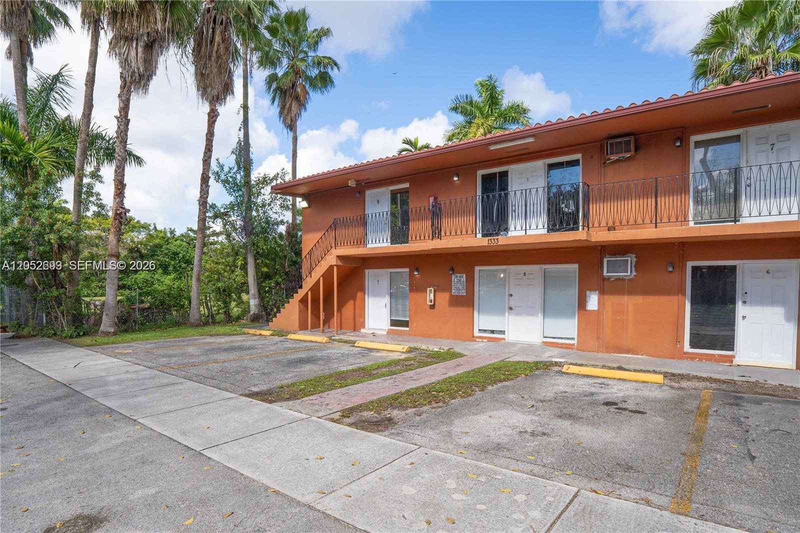 A two-story orange apartment building features exterior staircases, balconies, and a paved parking lot — 1333 NW 15th St # 10, Miami FL 33125, MIAMI, FL