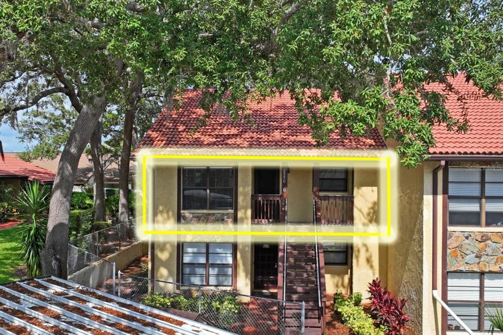 A two-story apartment building exterior featuring a highlighted upper-level balcony and staircase — 8550 SHADBLOW CT UNIT #6, PORT RICHEY, FL