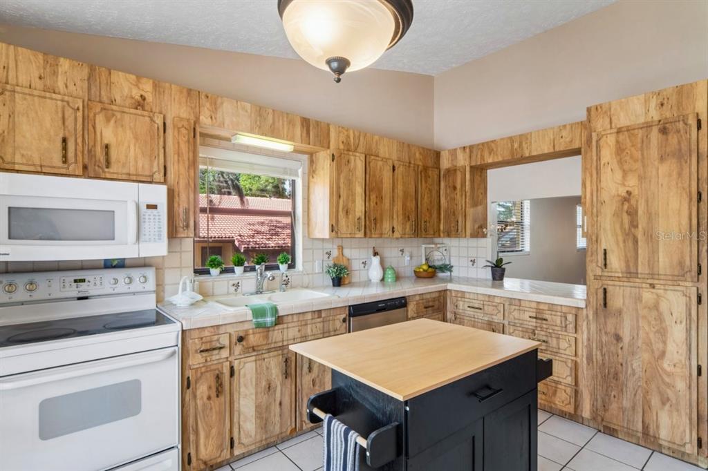 A kitchen with light wood cabinets, white tile countertops, a white stove, and a black island — 8550 SHADBLOW CT UNIT #6, PORT RICHEY, FL