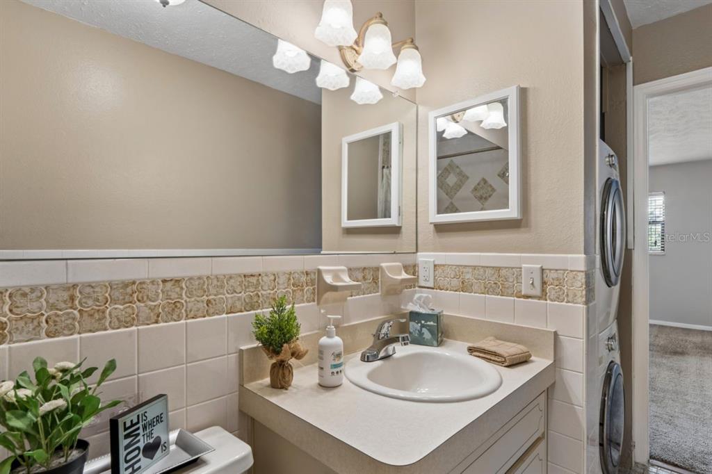 A bathroom features a vanity with a sink, a mirror, and a stacked laundry unit — 8550 SHADBLOW CT UNIT #6, PORT RICHEY, FL
