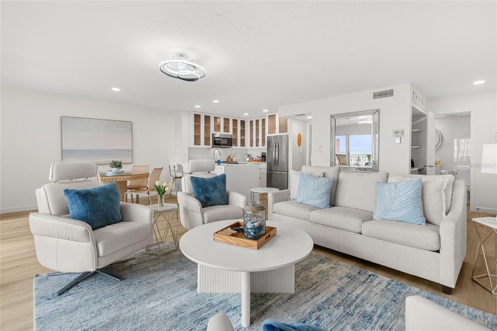 A bright, open-concept living room features a white sofa, two armchairs, and a kitchen area — 711 BEACH ROAD UNIT 408, SARASOTA, FL