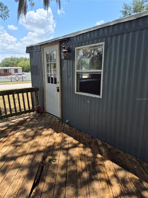 A dark gray mobile home features a wooden deck and a small white planter — 9285 SE 140TH PLACE, SUMMERFIELD, FL