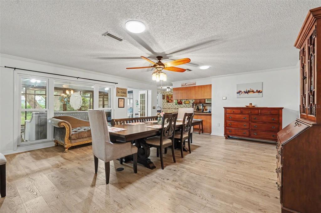 A dining room features a wooden table, upholstered chairs, light wood flooring, and a ceiling fan — 8251 EARLSHIRE LANE, SPRING HILL, FL