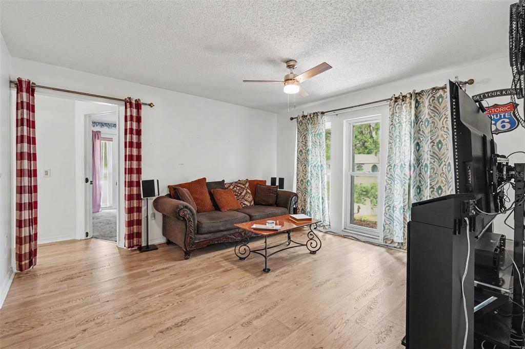 A living room features light wood flooring, a brown sofa, and a ceiling fan — 8251 EARLSHIRE LANE, SPRING HILL, FL