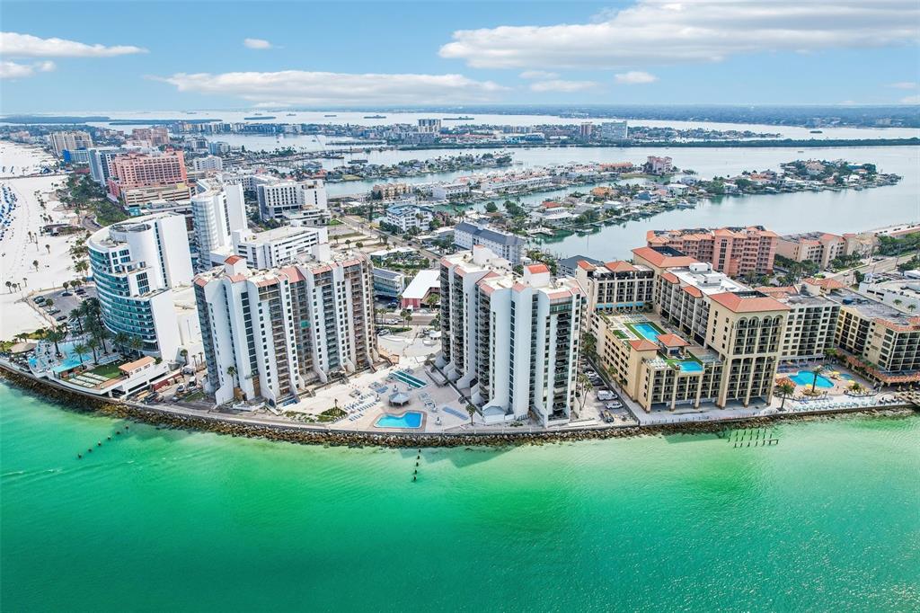 An aerial view of beachfront high-rise condominiums and resorts along a turquoise coastline — 450 S GULFVIEW BOULEVARD UNIT 605, CLEARWATER BEACH, FL