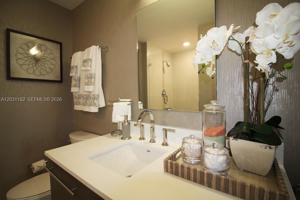 A modern bathroom features a white vanity sink, a large mirror, and decorative orchid plants — 7751 NW 107th Ave # 805, Doral FL 33178, DORAL, FL