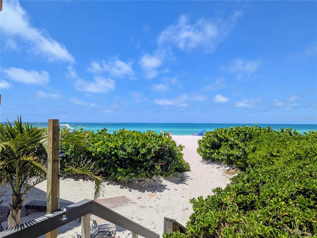A sandy path leads through green shrubs toward the ocean under a blue sky — 6006 GULF DRIVE UNIT 207, HOLMES BEACH, FL