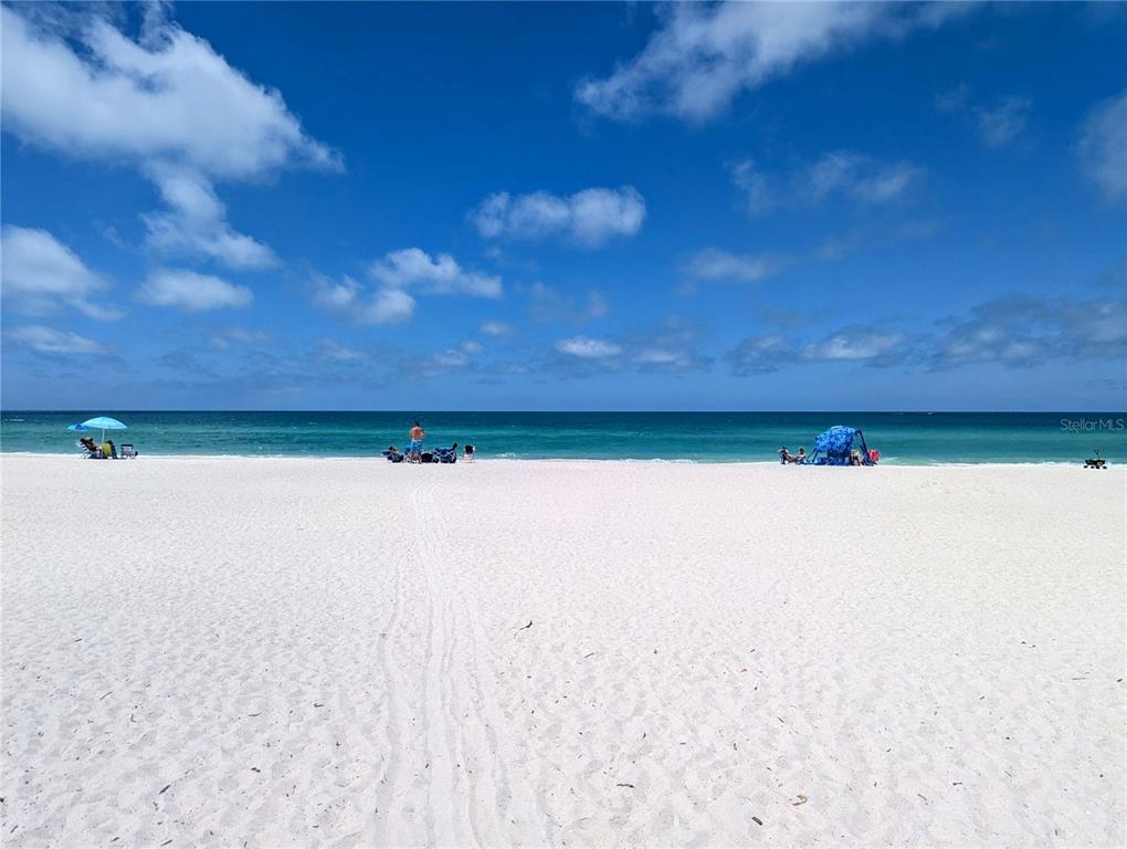 A wide, white sand beach meets the turquoise ocean under a bright blue sky — 6006 GULF DRIVE UNIT 207, HOLMES BEACH, FL