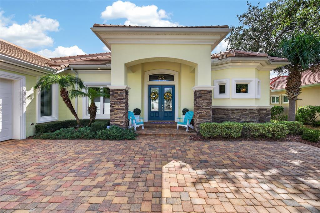 A yellow house with a stone-accented entryway, blue double doors, and a brick paver driveway — 28 N WATERVIEW DRIVE, PALM COAST, FL