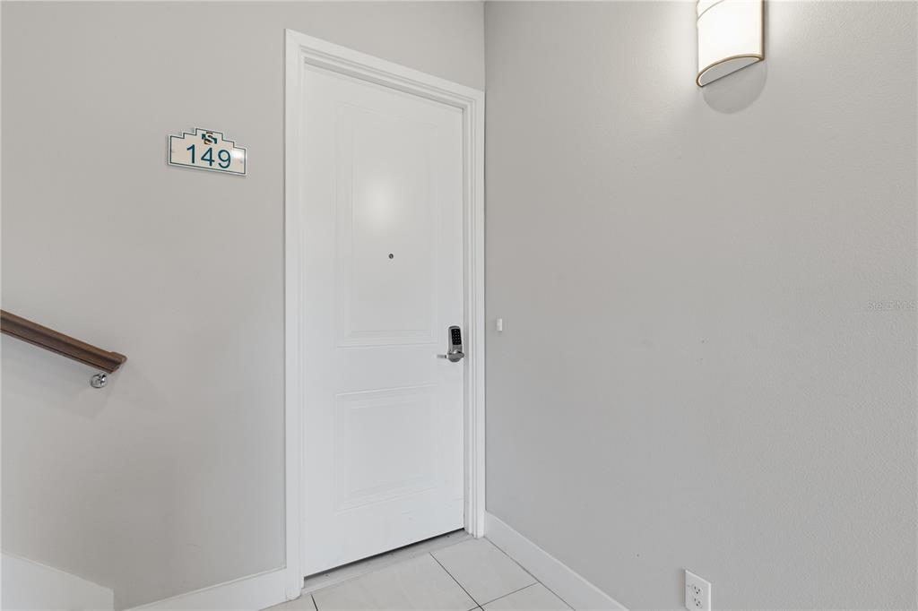 A white door with a digital lock and unit number 149 is in a hallway — 7740 SANDY RIDGE DRIVE UNIT 149, REUNION, FL