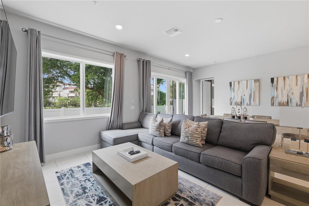 A living room features a gray sectional sofa, a wooden coffee table, and large windows — 7740 SANDY RIDGE DRIVE UNIT 149, REUNION, FL