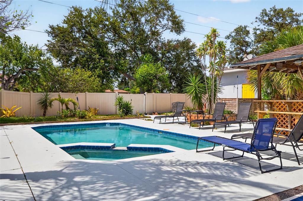 A backyard swimming pool with a spa, lounge chairs, and a wooden gazebo — 166 PINELLAS WAY N, ST PETERSBURG, FL