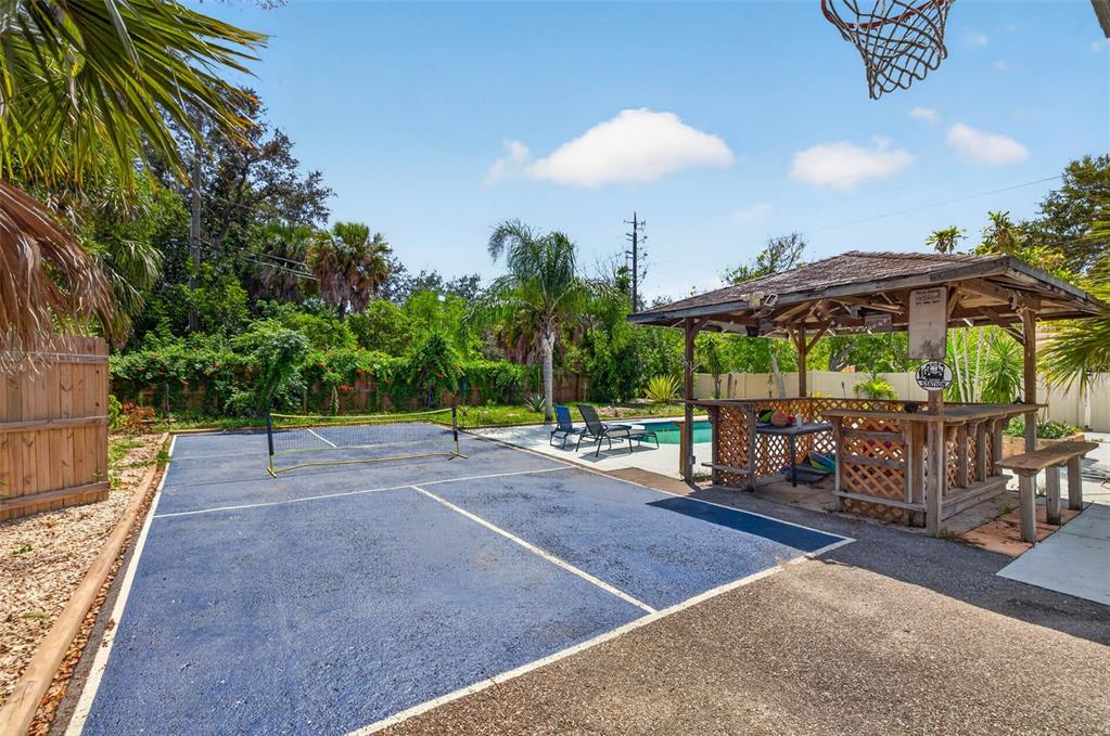 A backyard features a pickleball court, a wooden tiki bar, and a swimming pool — 166 PINELLAS WAY N, ST PETERSBURG, FL