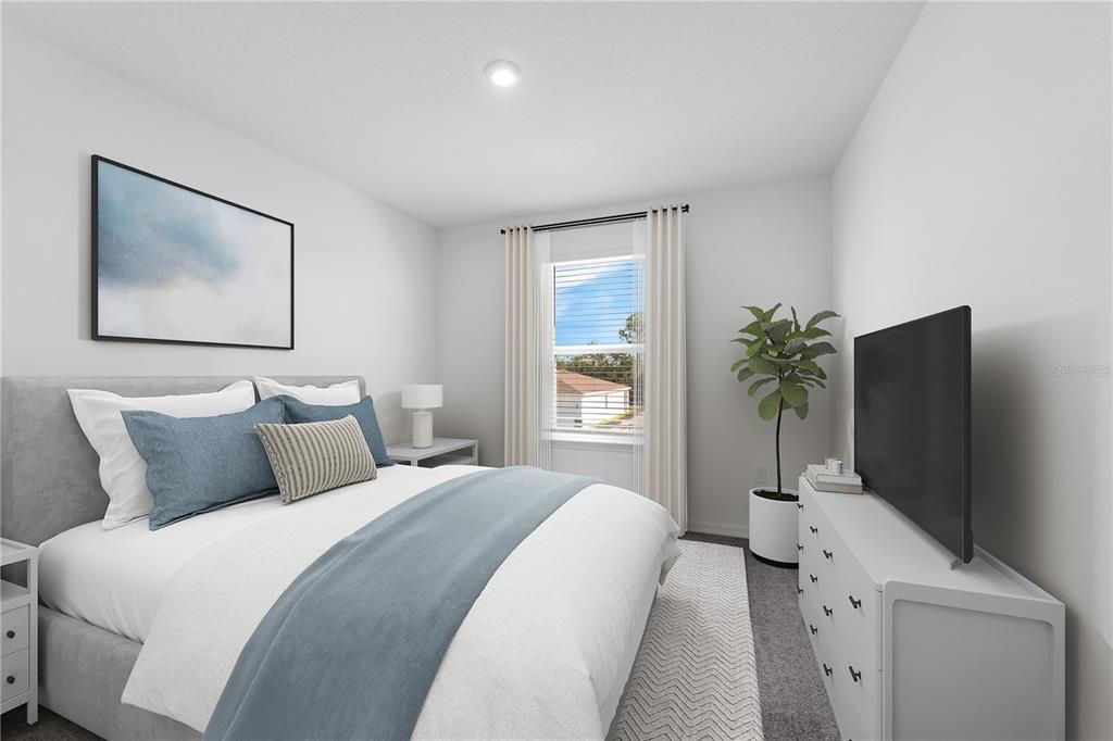 A bedroom features a gray upholstered bed, a white dresser with a television, and a window — 10165 HUNTINGNET WAY, LEESBURG, FL