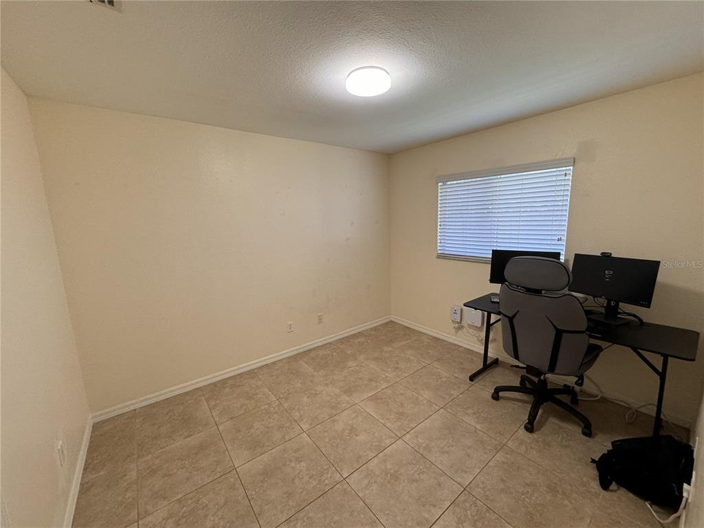 A room with beige walls, tile flooring, a window with blinds, and a computer desk — 3806 SW 6TH AVENUE, CAPE CORAL, FL