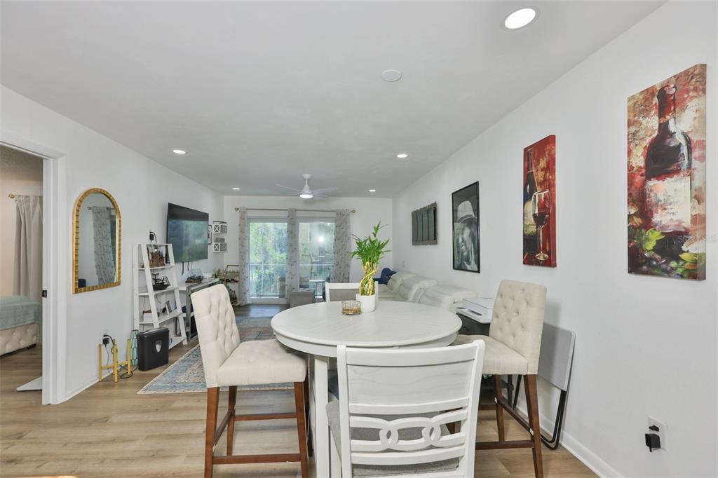A dining area with a round white table and chairs sits in an open-concept living space — 2625 STATE ROAD 590 UNIT 1121, CLEARWATER, FL