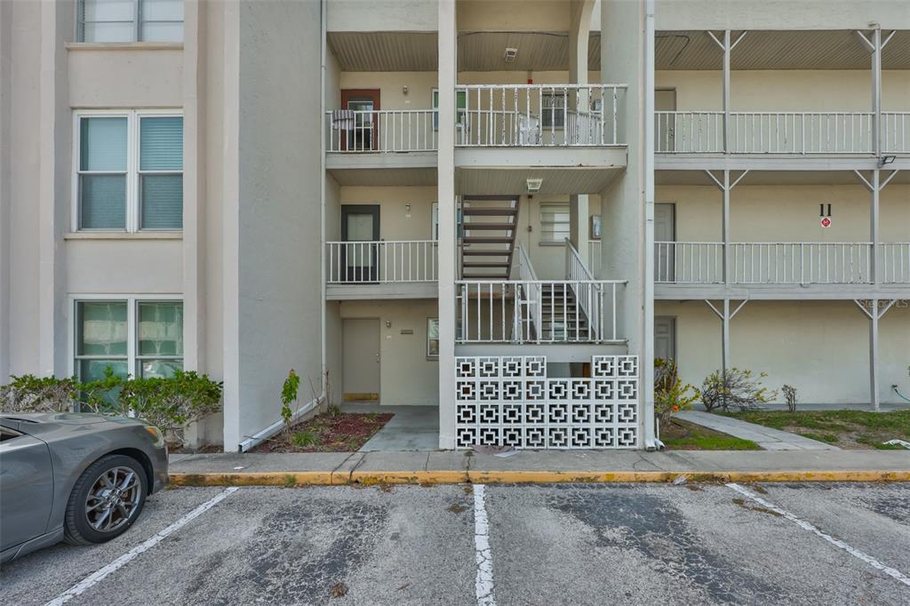An exterior view of a multi-story apartment building with concrete stairs and a parking lot — 2625 STATE ROAD 590 UNIT 1121, CLEARWATER, FL