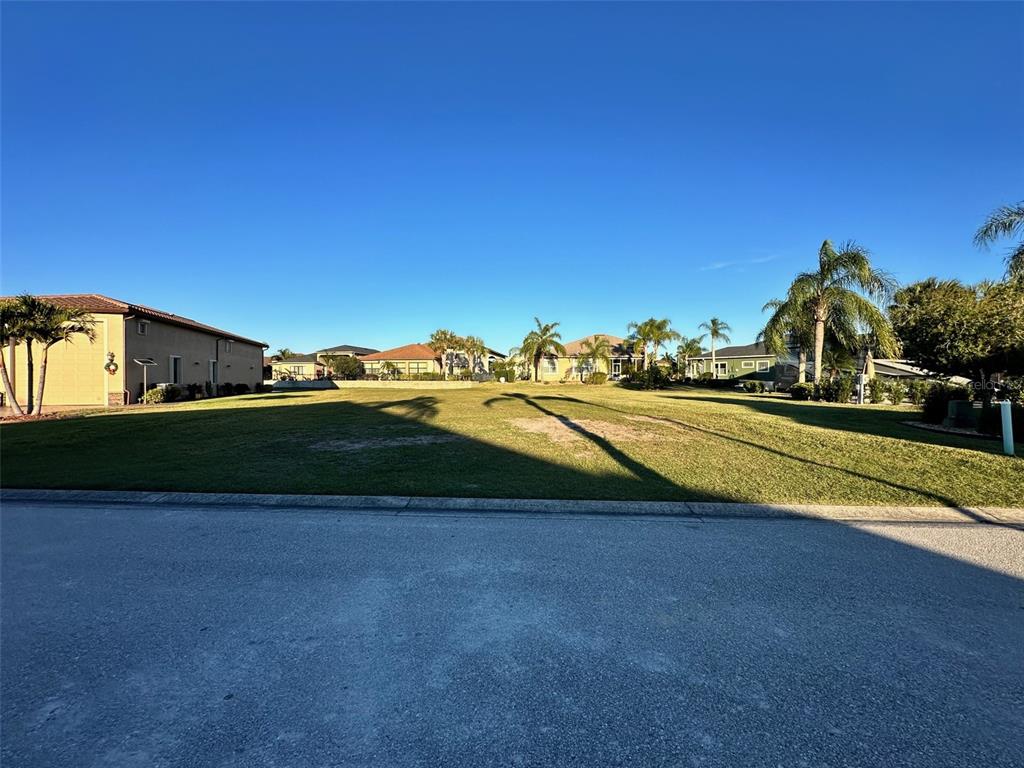A vacant, grassy residential lot is situated between existing houses under a clear blue sky — 505 MEANDERING WAY, POLK CITY, FL
