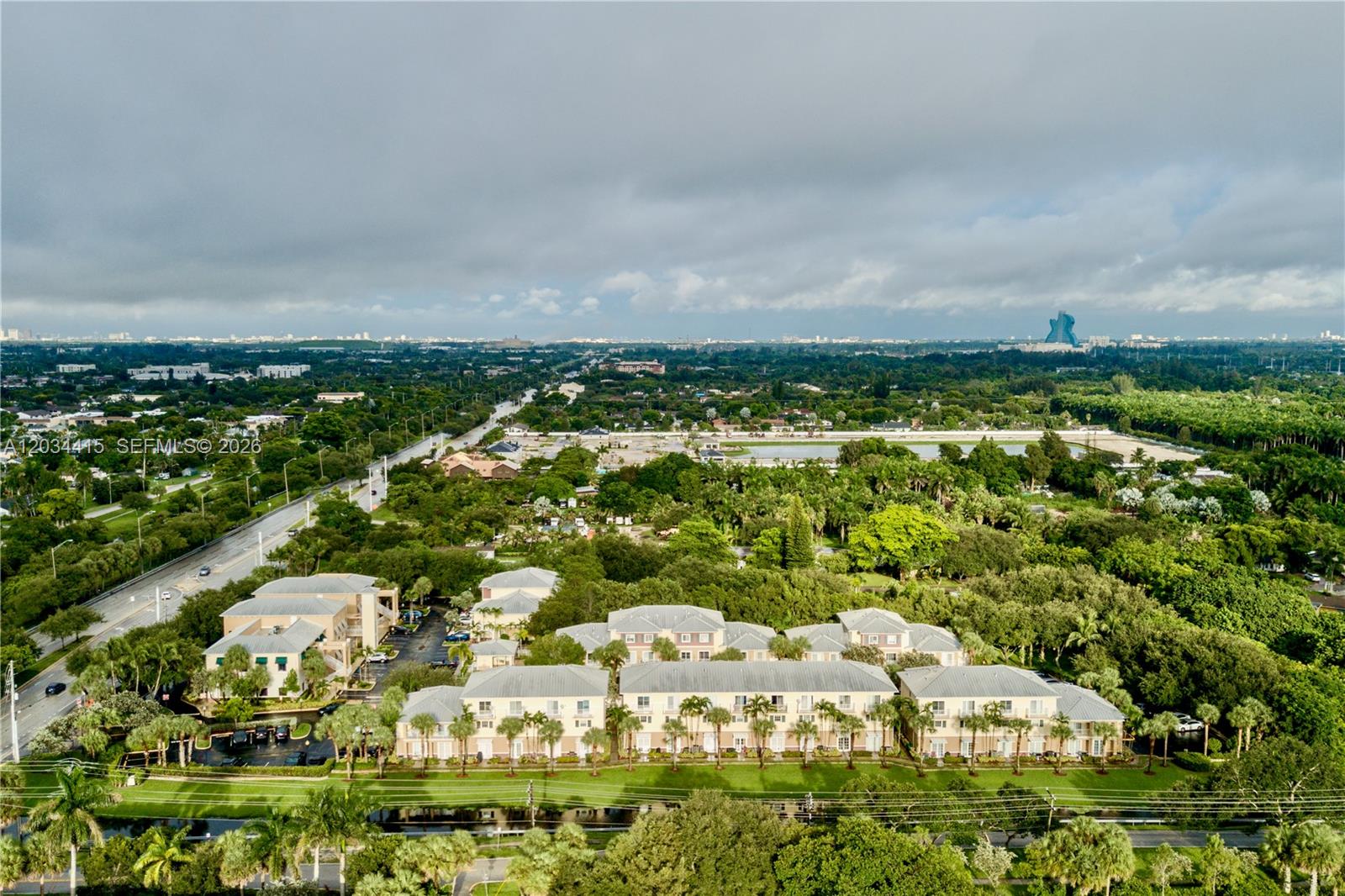An aerial view shows a multi-story apartment complex surrounded by lush trees and a road — 4649 SW 75th Way, Davie FL 33314, DAVIE, FL