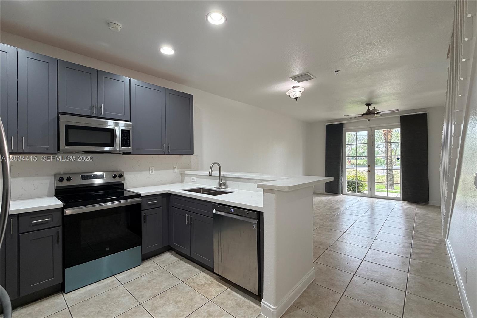 A kitchen with dark gray cabinets and white countertops opens into a tiled living area — 4649 SW 75th Way, Davie FL 33314, DAVIE, FL