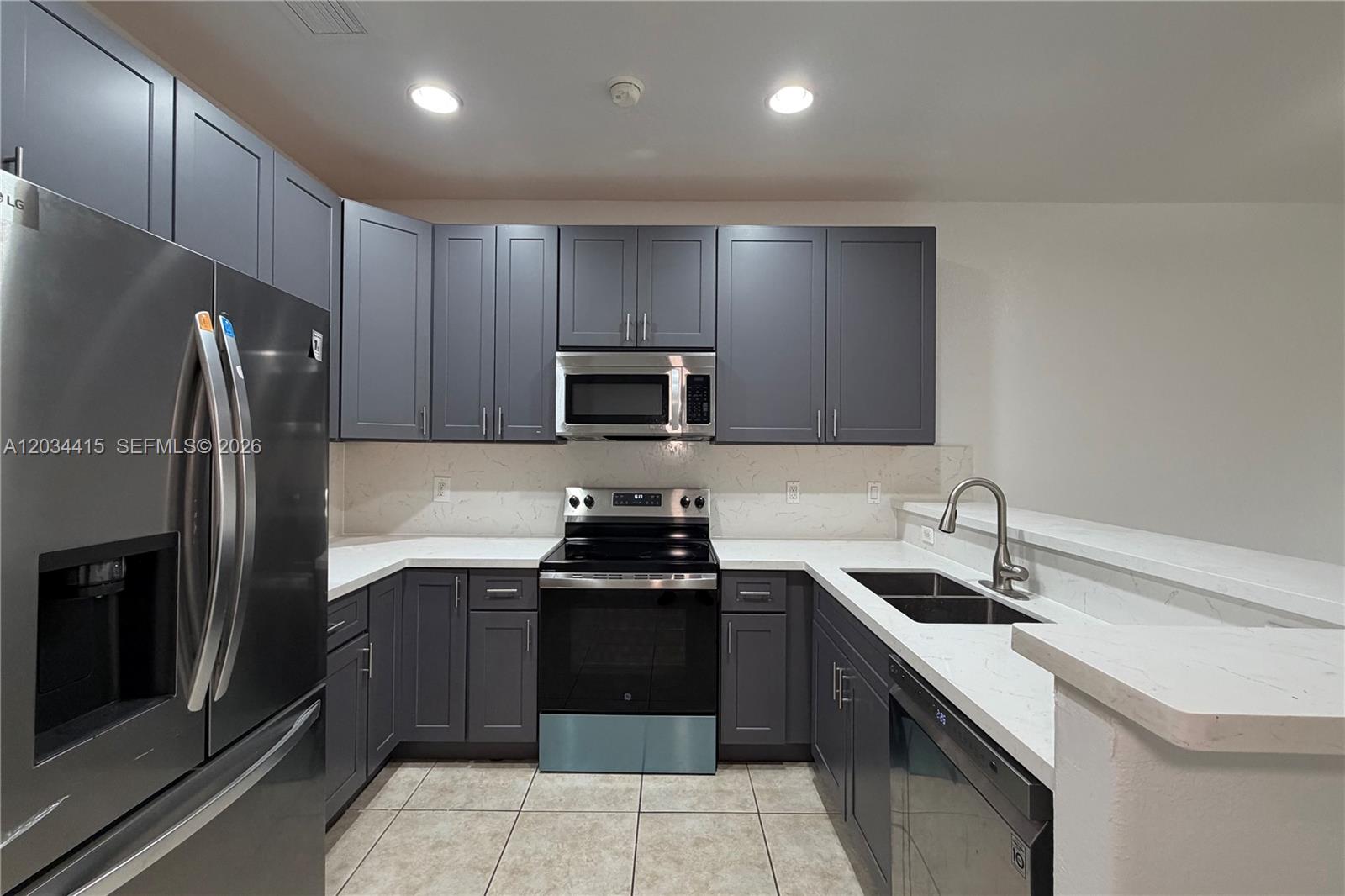 A kitchen features dark gray cabinets, stainless steel appliances, and white marble-look countertops — 4649 SW 75th Way, Davie FL 33314, DAVIE, FL