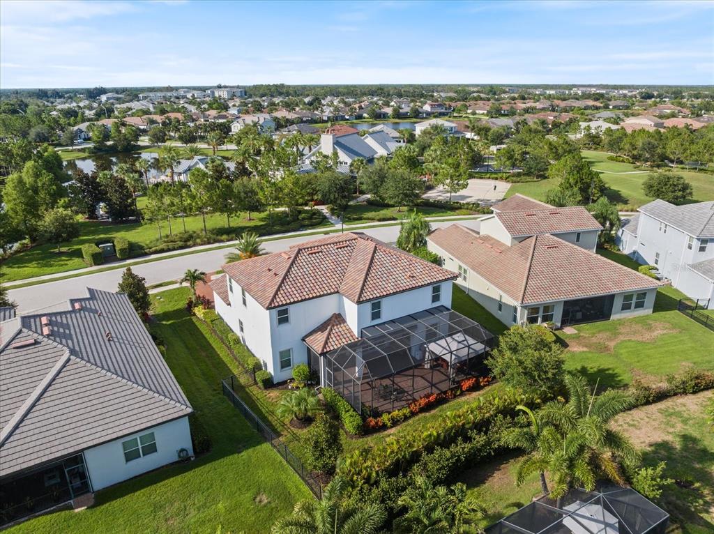 An aerial view shows suburban houses with tiled roofs, screened-in lanais, and landscaped backyards — 12120 GANNETT PLACE, LAKEWOOD RANCH, FL