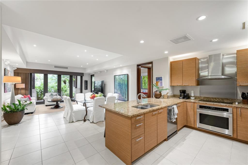 A kitchen with wood cabinets and granite countertops opens to a dining and living area — Bahia Beach Golf Club LAS VERANDAS CONDOMINIUM 3119 UNIT 3119, RIO GRANDE, PR