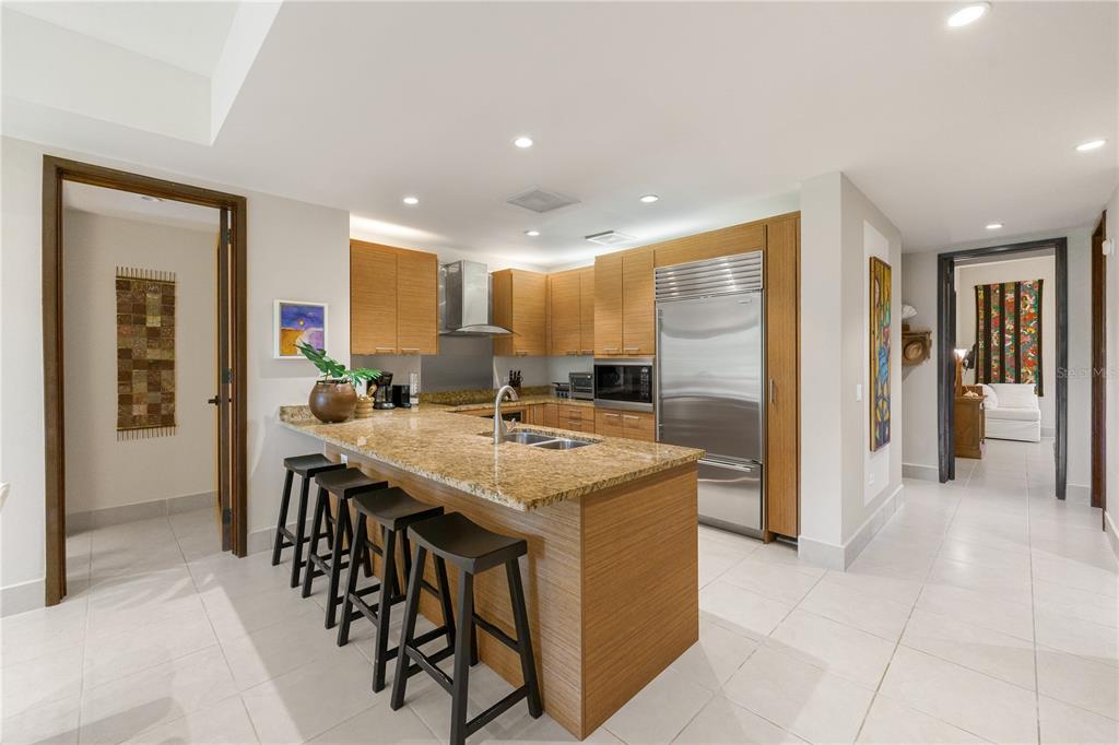 A modern kitchen features wood cabinets, granite countertops, a breakfast bar, and stainless steel appliances — Bahia Beach Golf Club LAS VERANDAS CONDOMINIUM 3119 UNIT 3119, RIO GRANDE, PR