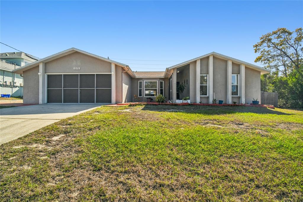 A single-story house with a beige stucco exterior, a two-car garage, and a front lawn — 13170 PIRATE LANE, SPRING HILL, FL