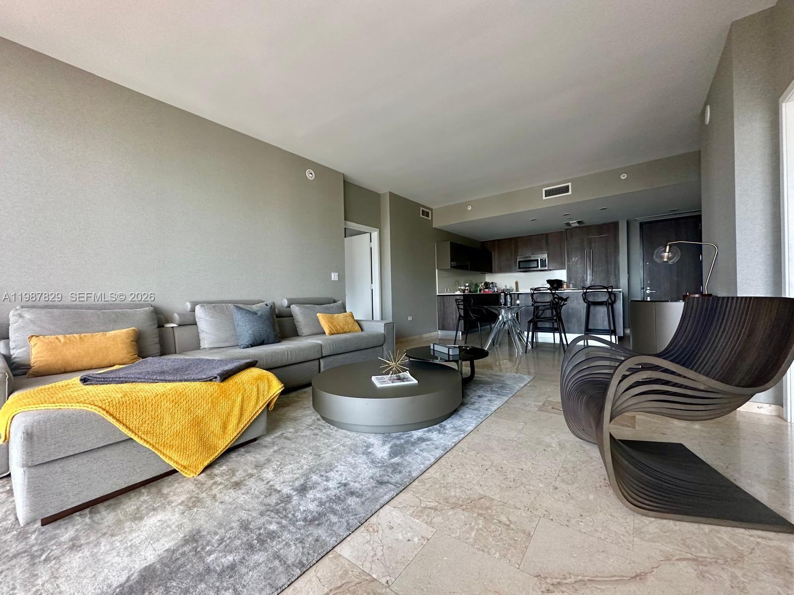 A living room features a grey sectional sofa, a round coffee table, and modern decor — 88 SW 7th St # 3609, Miami FL 33130, MIAMI, FL