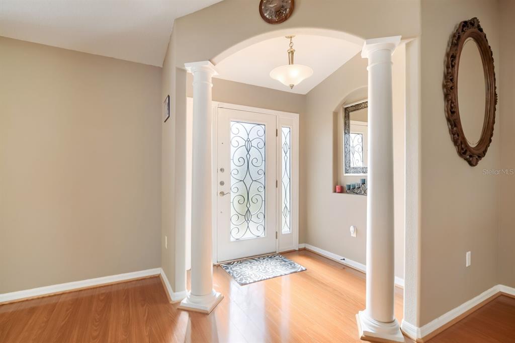 An entryway features hardwood floors, two white columns, an arched ceiling, and a glass-paneled door — 4460 MARSH HARBOR DRIVE, TAVARES, FL