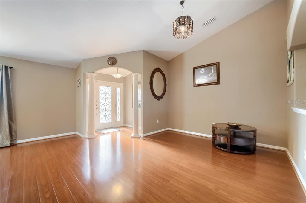 A living room with hardwood floors, a vaulted ceiling, and a white front entryway — 4460 MARSH HARBOR DRIVE, TAVARES, FL