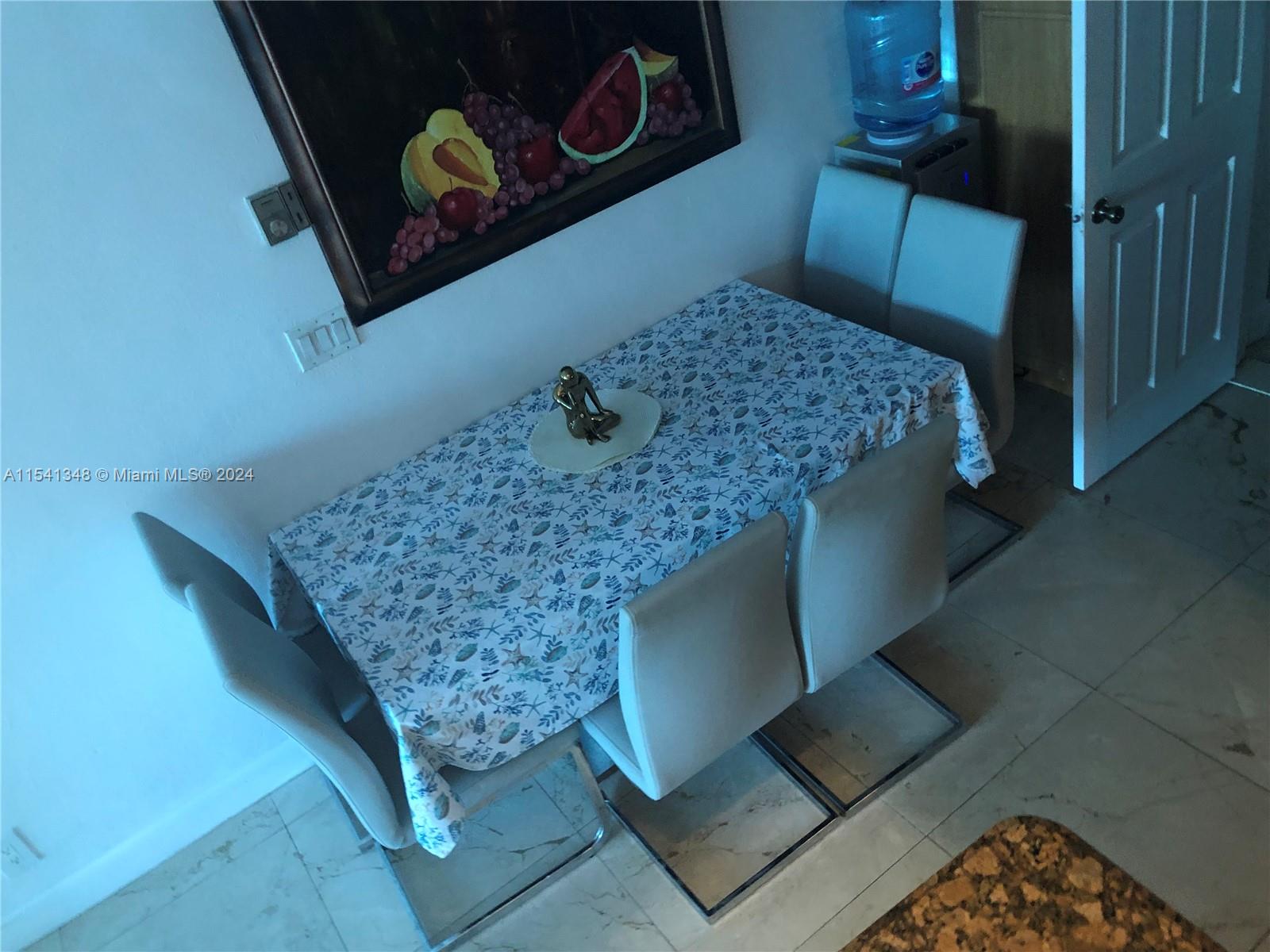 A dining area features a table with a patterned tablecloth, four chairs, and wall art — 5445 Collins Ave, Miami Beach FL 33140, MIAMI BEACH, FL