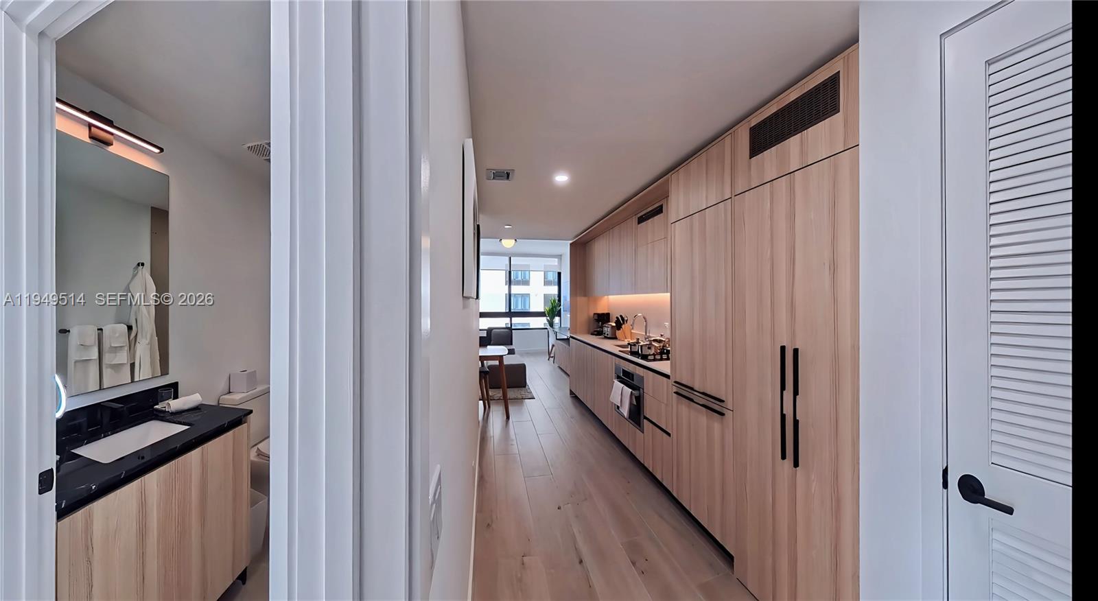 A hallway leads past a bathroom with a black vanity into a modern kitchen area — 225 N Miami Ave # 1812, Miami FL 33132, MIAMI, FL