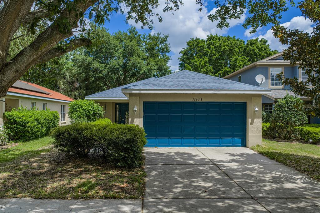 A single-story house with a blue garage door and a concrete driveway under trees — 11578 HAMMOCKS GLADE DRIVE, RIVERVIEW, FL