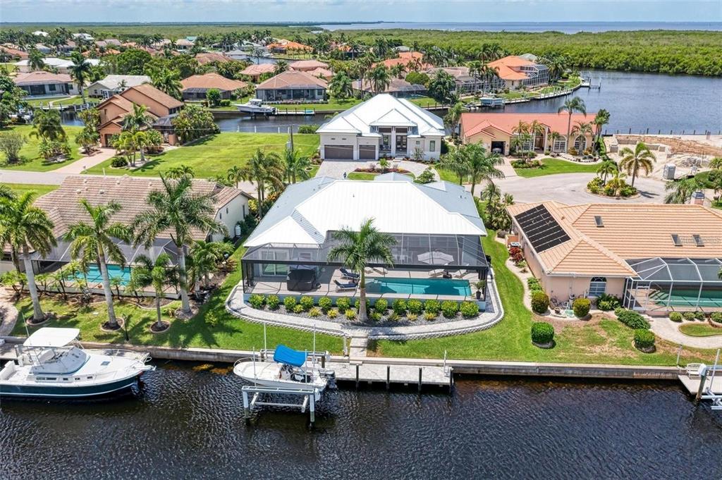 An aerial view shows a waterfront house with a pool, screened lanai, and boat dock — 1430 SEA GULL COURT, PUNTA GORDA, FL