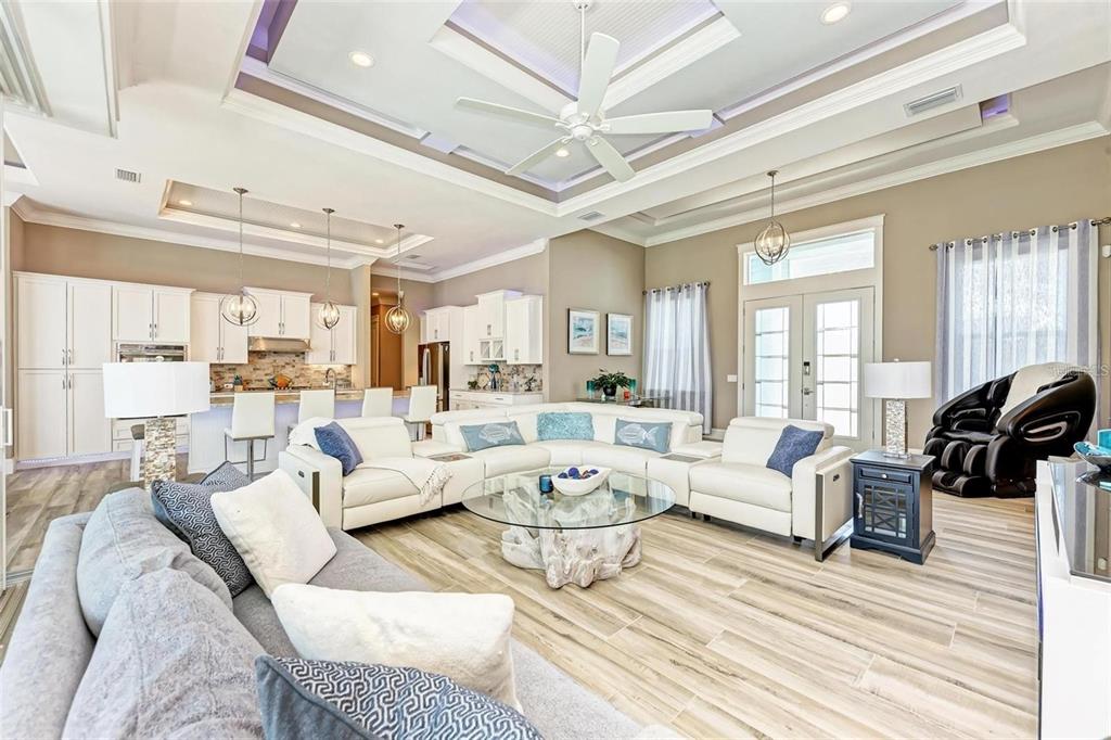 A spacious open-concept living room features white leather sectional seating, a glass coffee table, and kitchen — 1430 SEA GULL COURT, PUNTA GORDA, FL