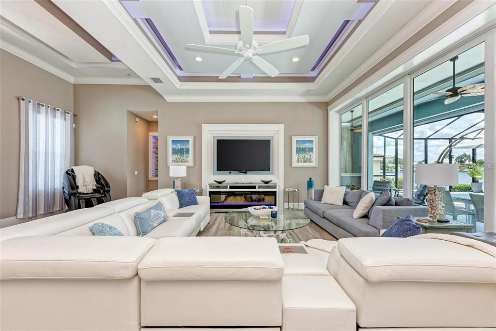 A living room features a white sectional, a gray sofa, a fireplace, and tray ceilings — 1430 SEA GULL COURT, PUNTA GORDA, FL