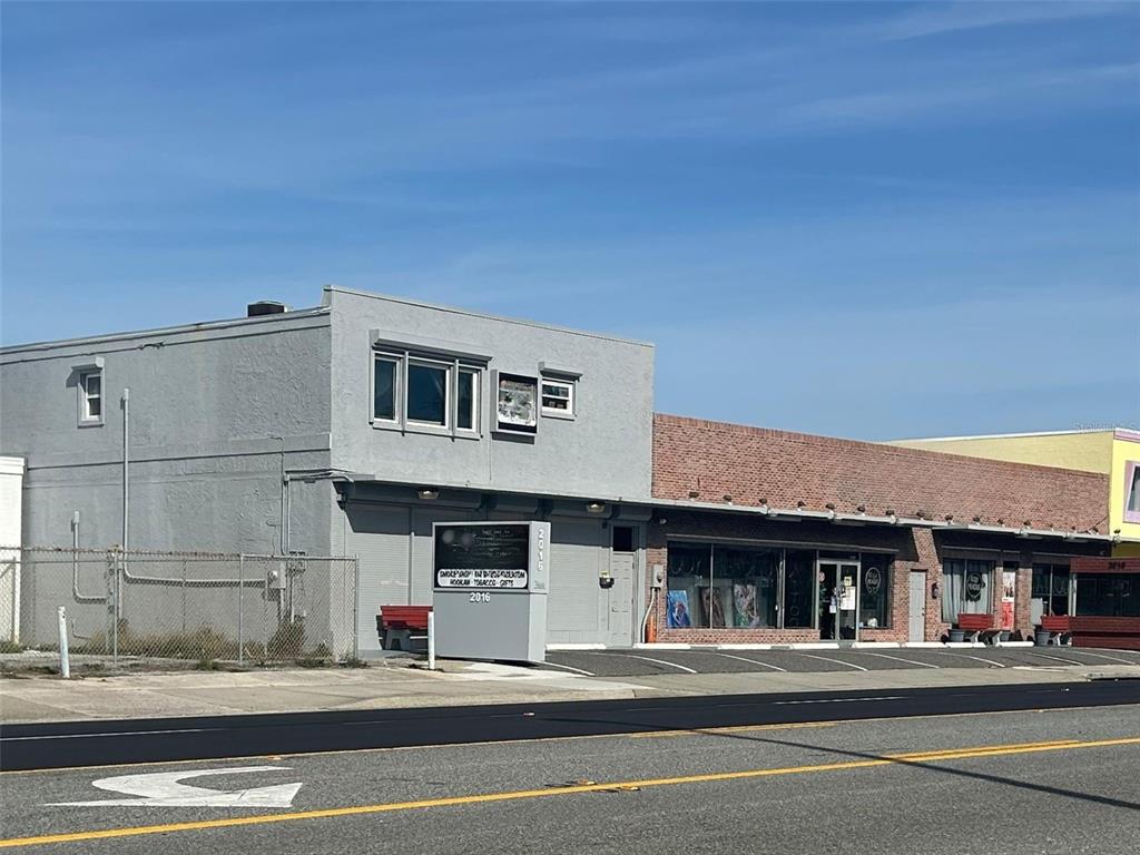 A two-story gray building and an adjacent single-story brick commercial building sit along a road — 2012 S ATLANTIC AVENUE, DAYTONA BEACH, FL