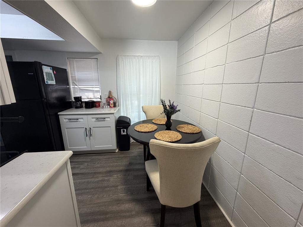A dining area features a round table, two chairs, white cabinets, and a block wall — 15219 WESTMINISTER AVENUE UNIT B, CLEARWATER, FL