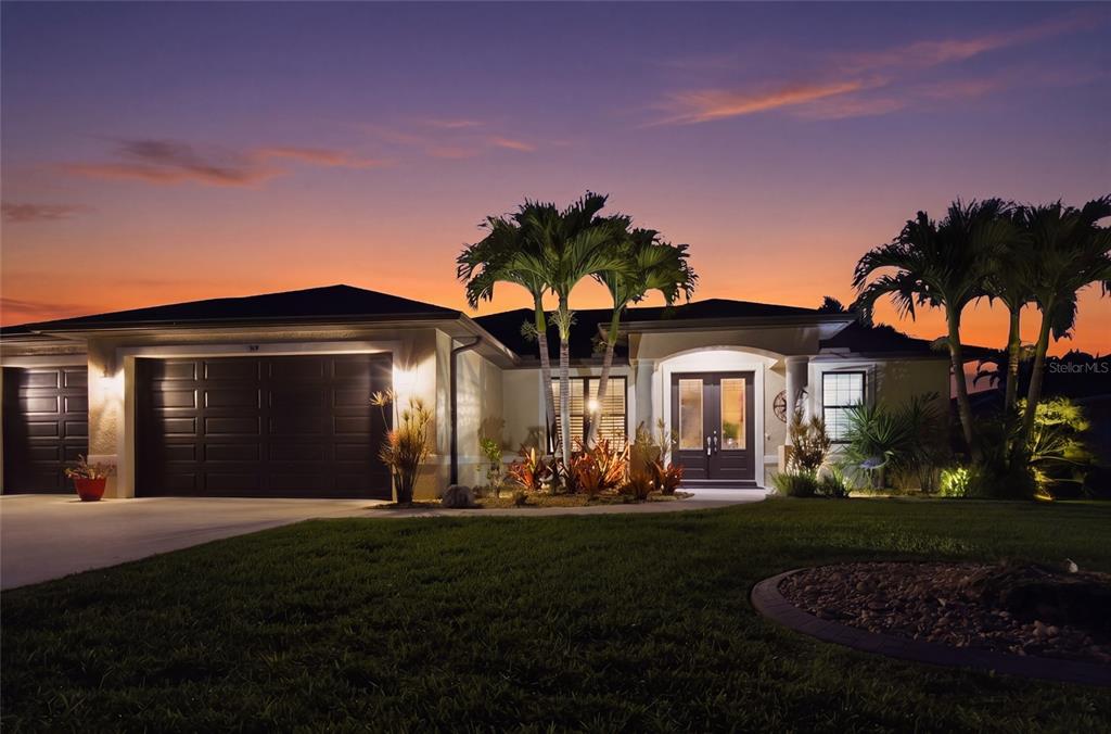 A single-story house with a dark garage, double front doors, and palm trees at dusk — 39 MEDALIST ROAD, ROTONDA WEST, FL