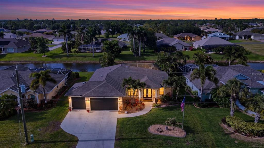 An aerial view shows a single-story house with a garage, pool cage, and canal backyard — 39 MEDALIST ROAD, ROTONDA WEST, FL