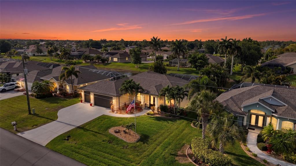 An aerial view of a suburban house with a driveway and palm trees at sunset — 39 MEDALIST ROAD, ROTONDA WEST, FL