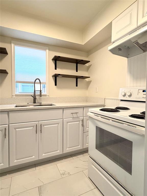 A kitchen features white cabinets, a white stove, open wood shelving, and a window — 432 E STREET UNIT 432, CASSELBERRY, FL