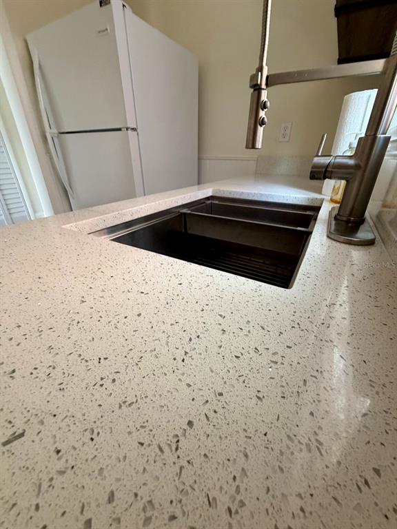 A kitchen sink with a modern faucet is set into a speckled white quartz countertop — 432 E STREET UNIT 432, CASSELBERRY, FL