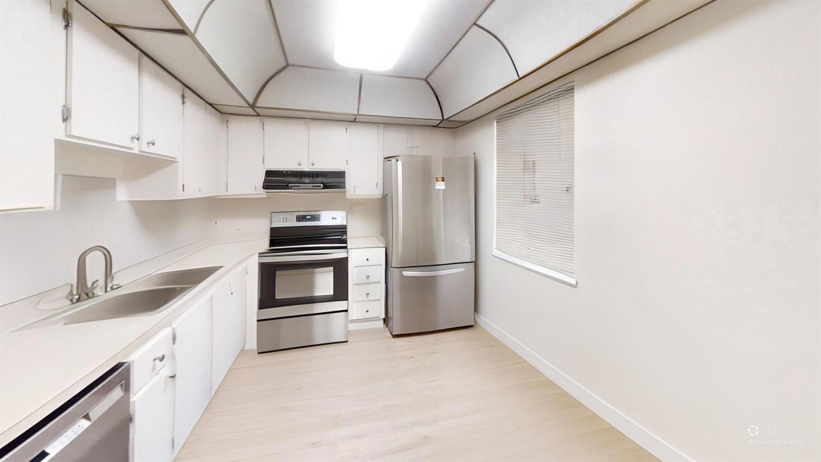 A kitchen features white cabinets, stainless steel appliances, and light-colored flooring under a tray ceiling — 101 SE 3rd Avenue # 605, Dania Beach FL 33004, DANIA BEACH, FL