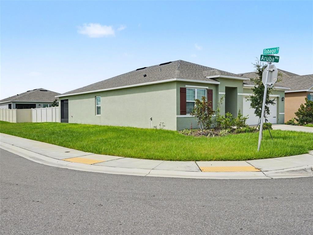 A light green single-story house sits on a corner lot at a street intersection — 3362 ARUBA WAY, HAINES CITY, FL