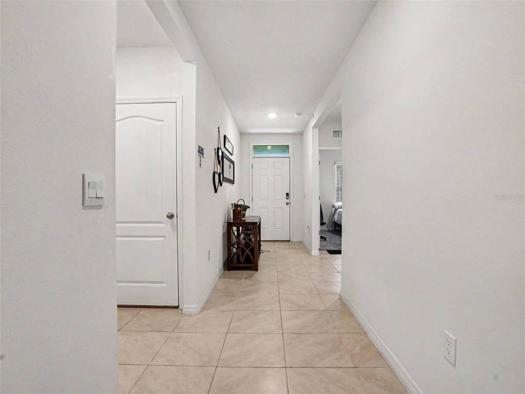 A tiled entryway leads to a white front door with a small wooden console table — 3362 ARUBA WAY, HAINES CITY, FL